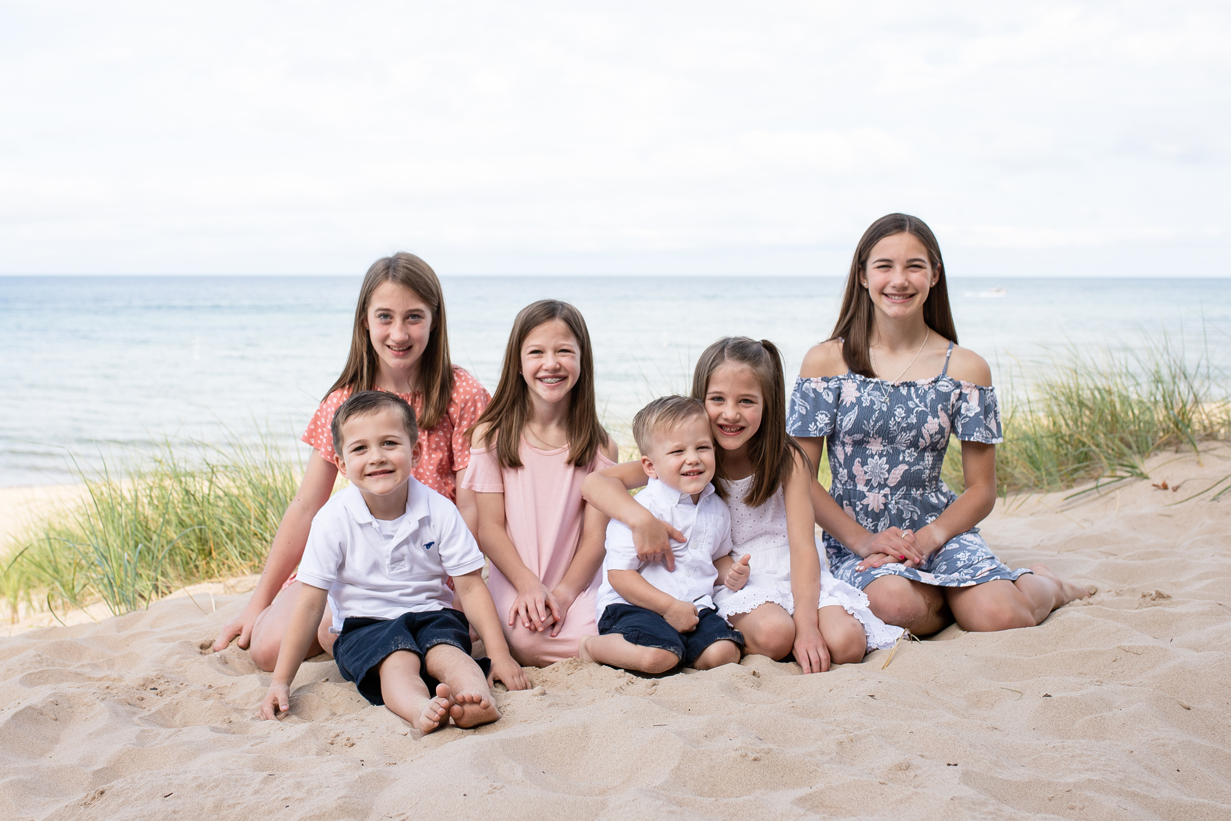 Smiling children sitting in the sand with Lake Michigan behind them